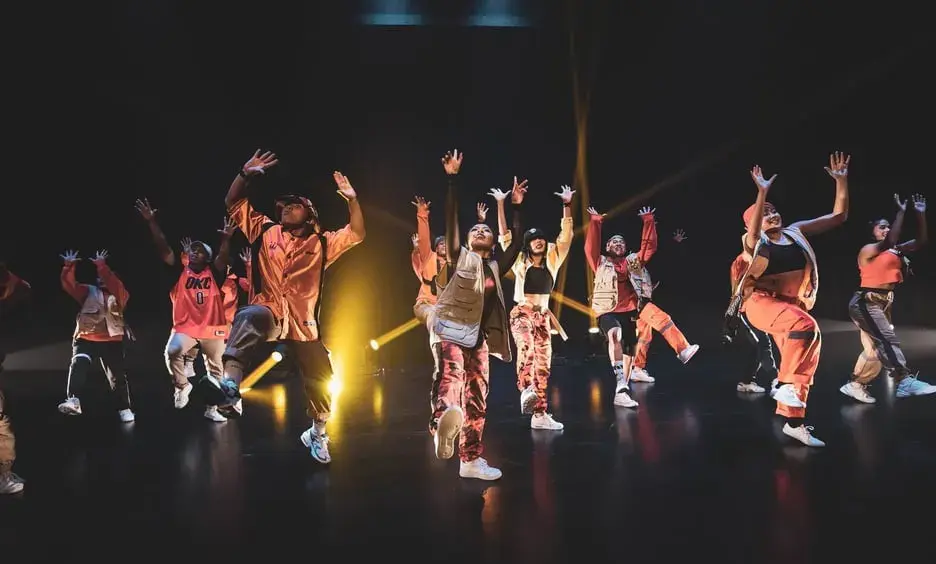 Dancers in orange outfits performing on stage
